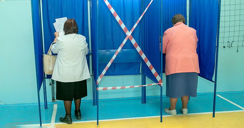 Женщины голосуют в кабинках для голосования