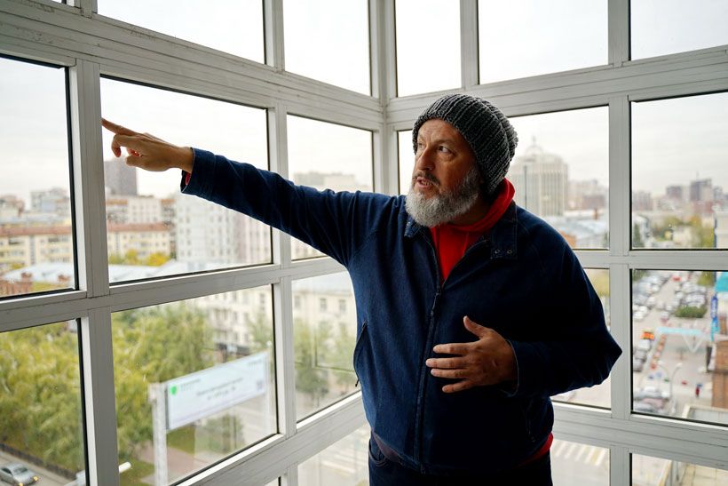 Олег Викторович показывает пальцем на здание