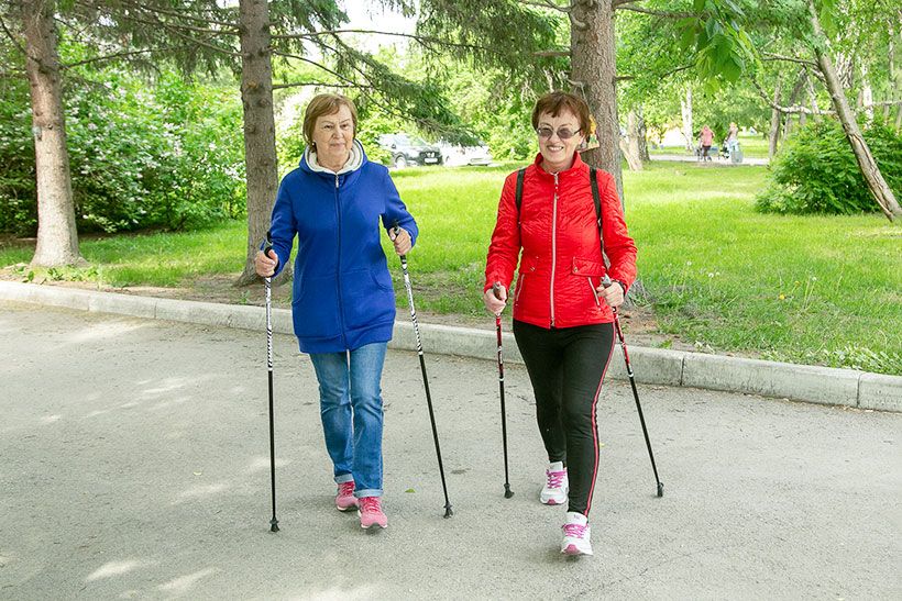 Пожилые женщины с лыжными палками занимаются скандинавской ходьбой