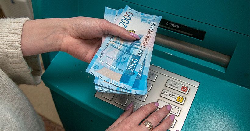 женская рука кладёт деньги в банкомат
