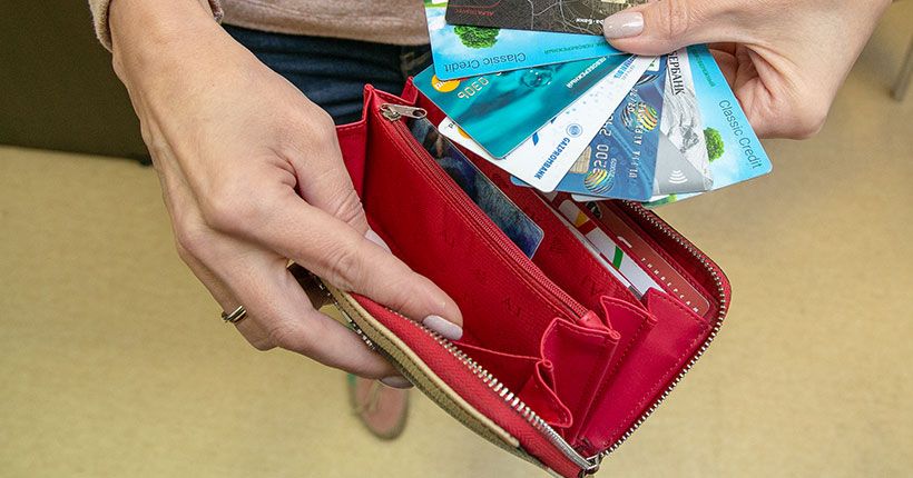Девушка заглядывает в кошелек где лежат кредитные карты