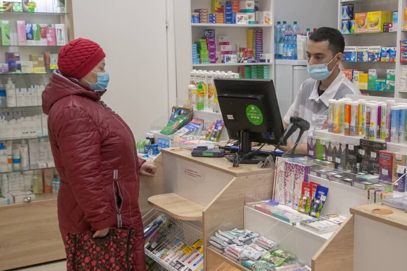 Женщина в маске покупает лекарства в аптеке