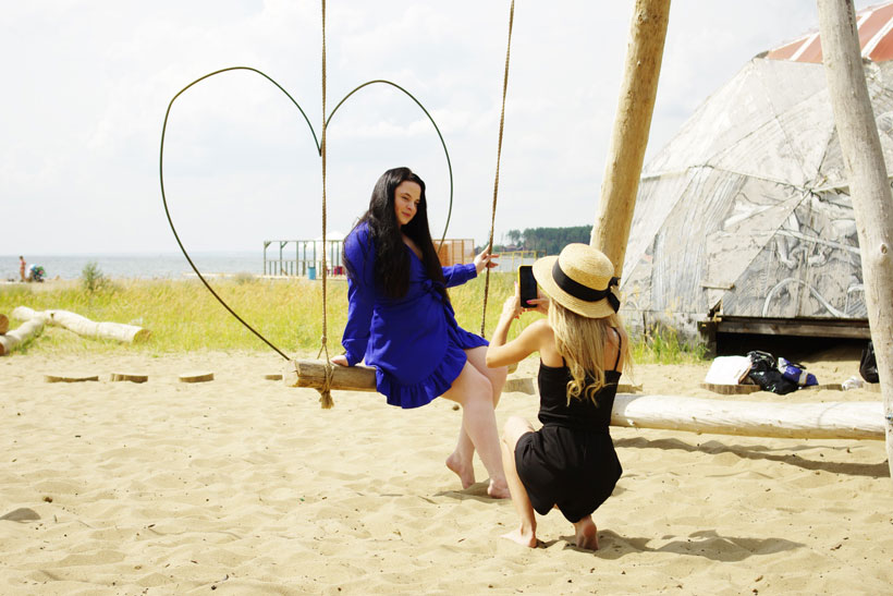 Девушки фотографируются на качелях на фоне пляжа Академгородка