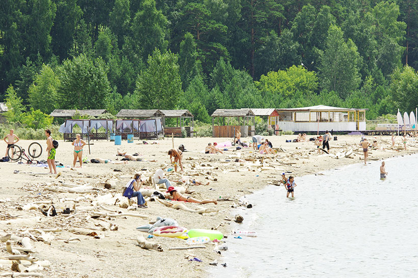 Отдыхающие загорают среди мусора на центральном пляже Академгородка