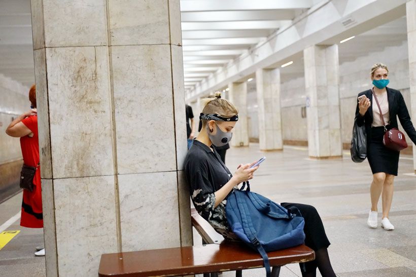 Подросток в маске сидит на скамейке в метрополитене