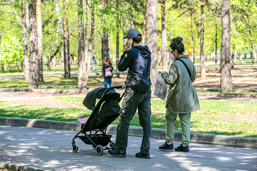 Семья с коляской на прогулке в парке