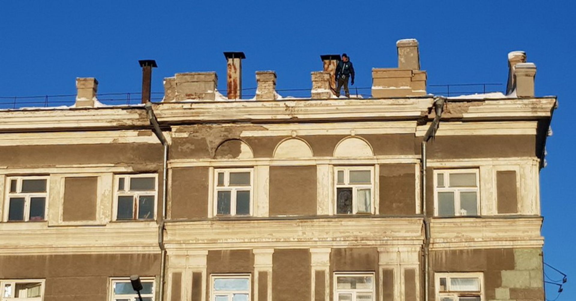 рабочий чистит крышу от снега