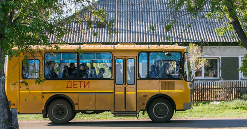 автобус с детьми движется по сельской дороге